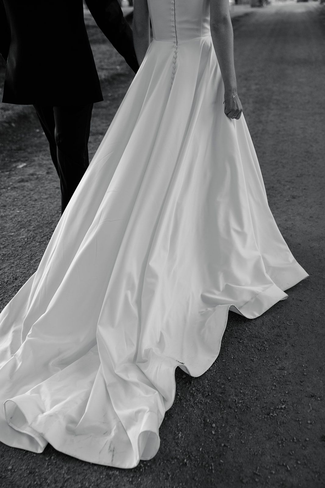 A series of black and white photos showing the flowing train of a white wedding dress against a dark ground.