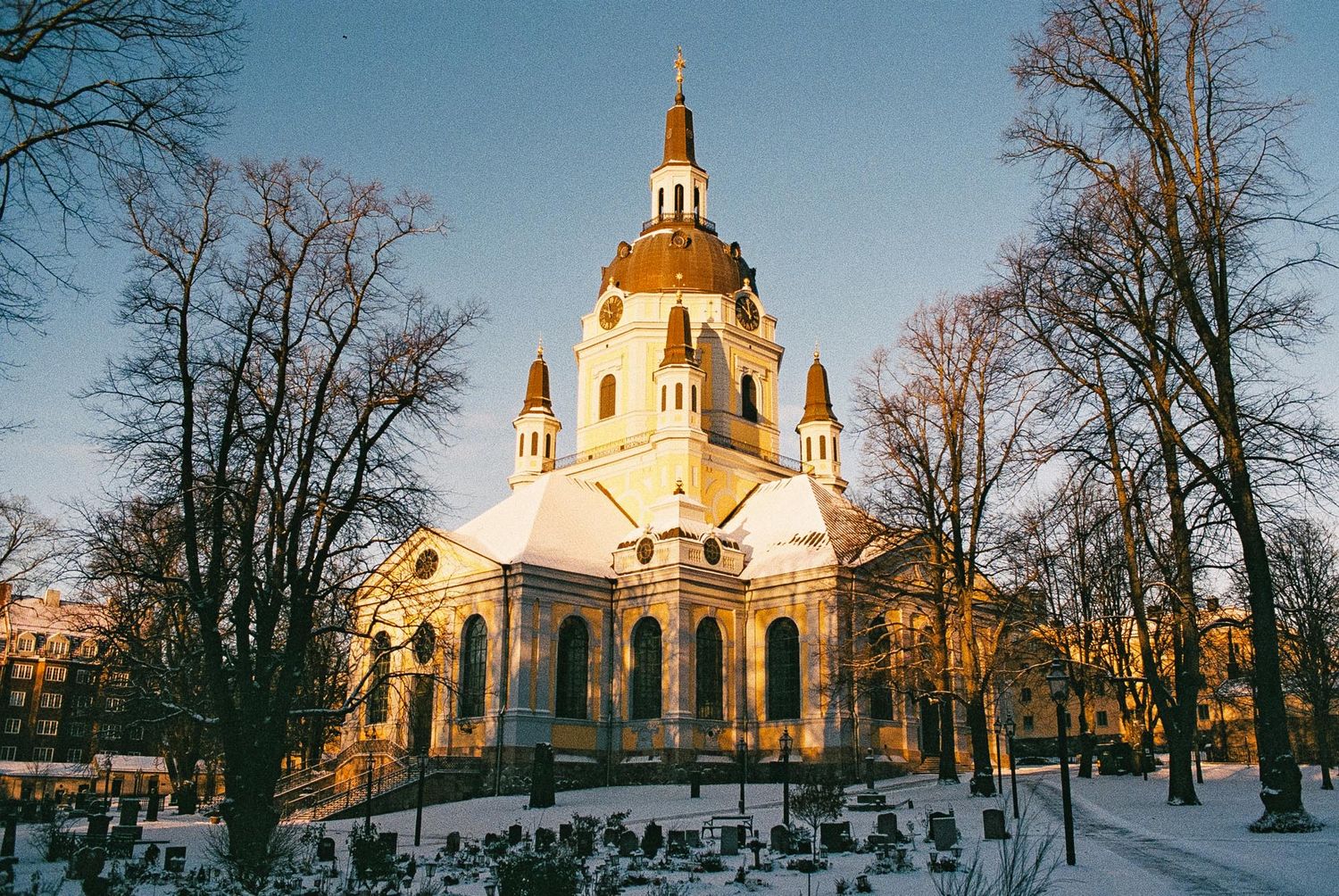 Golden-domed Orthodox church with multiple spires photographed from different angles in winter against bare trees.