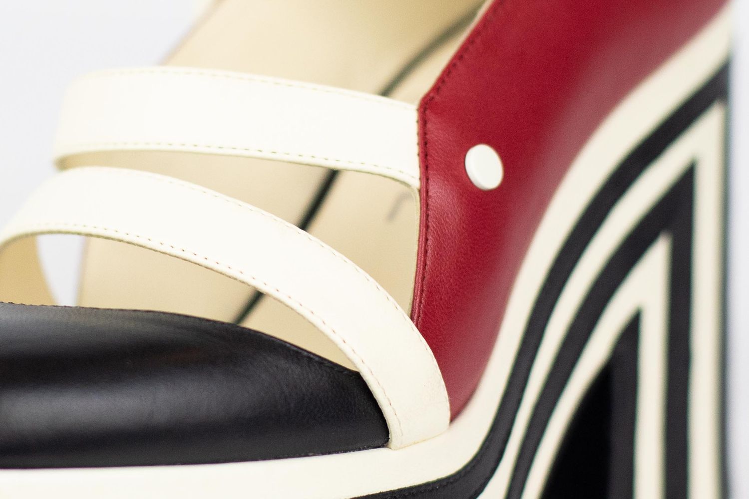 Close-up view of a Woman's Shoe showing red and white leather with detailed stitching patterns.