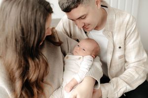 A series of tender moments between parents and their newborn baby in white outfits against a neutral background.