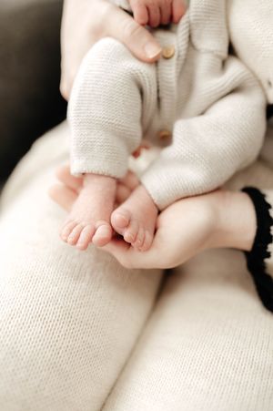 Close-up of tiny baby feet wrapped in soft white knit fabric showing delicate toes and skin texture.