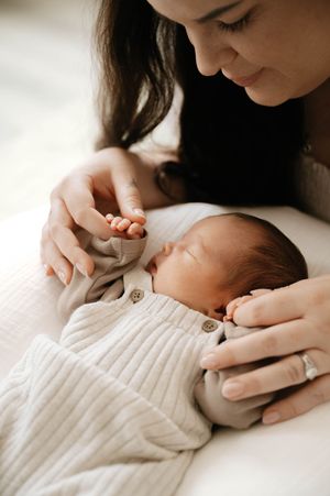 A tender moment between parent and newborn baby wrapped in soft white knit clothing.