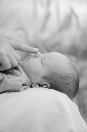 A sleeping baby lies peacefully in black and white tones against a soft blurred background.