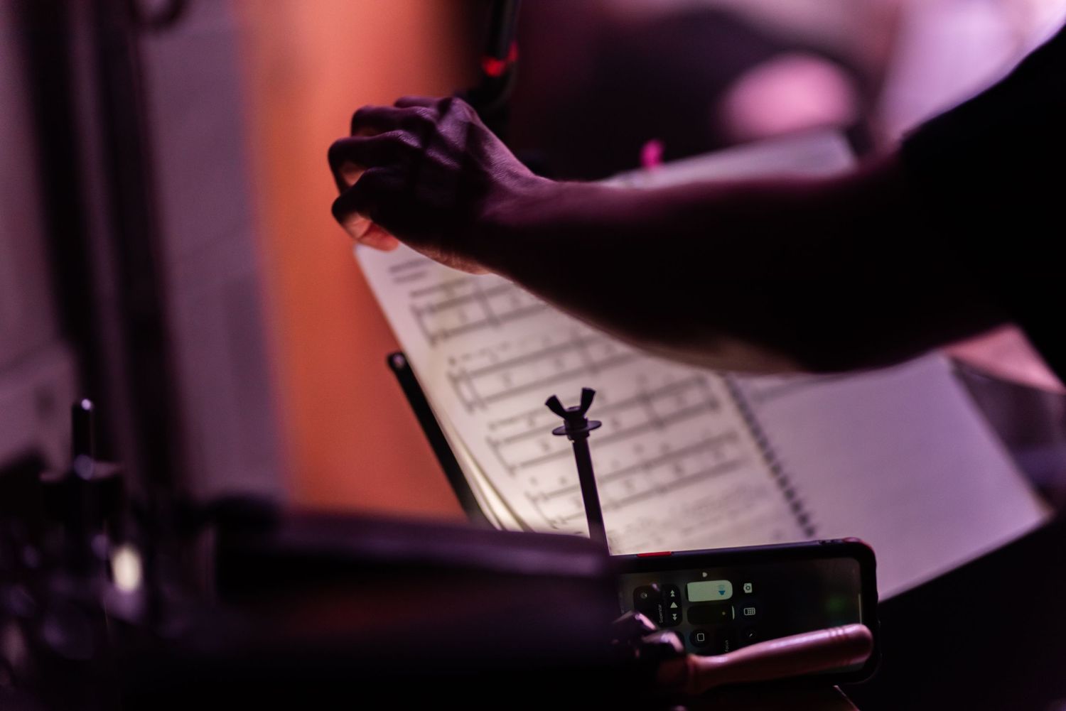 Close-up of musical instruments and sheet music under dramatic red stage lighting.