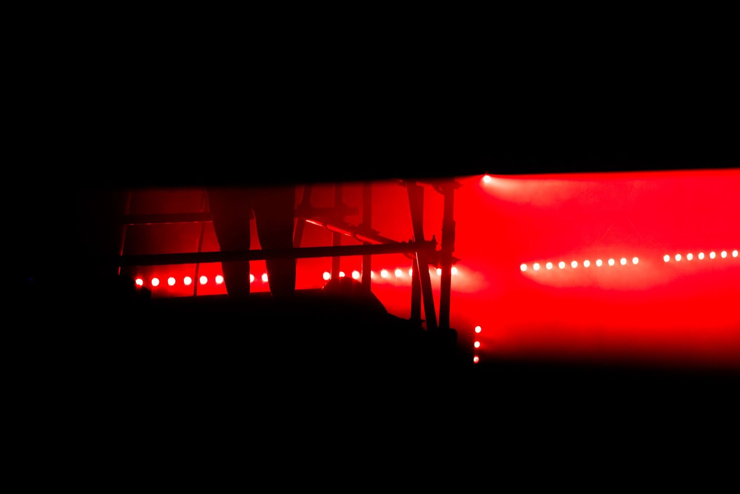 Dramatic red lighting effect creating silhouettes in dark performance space.