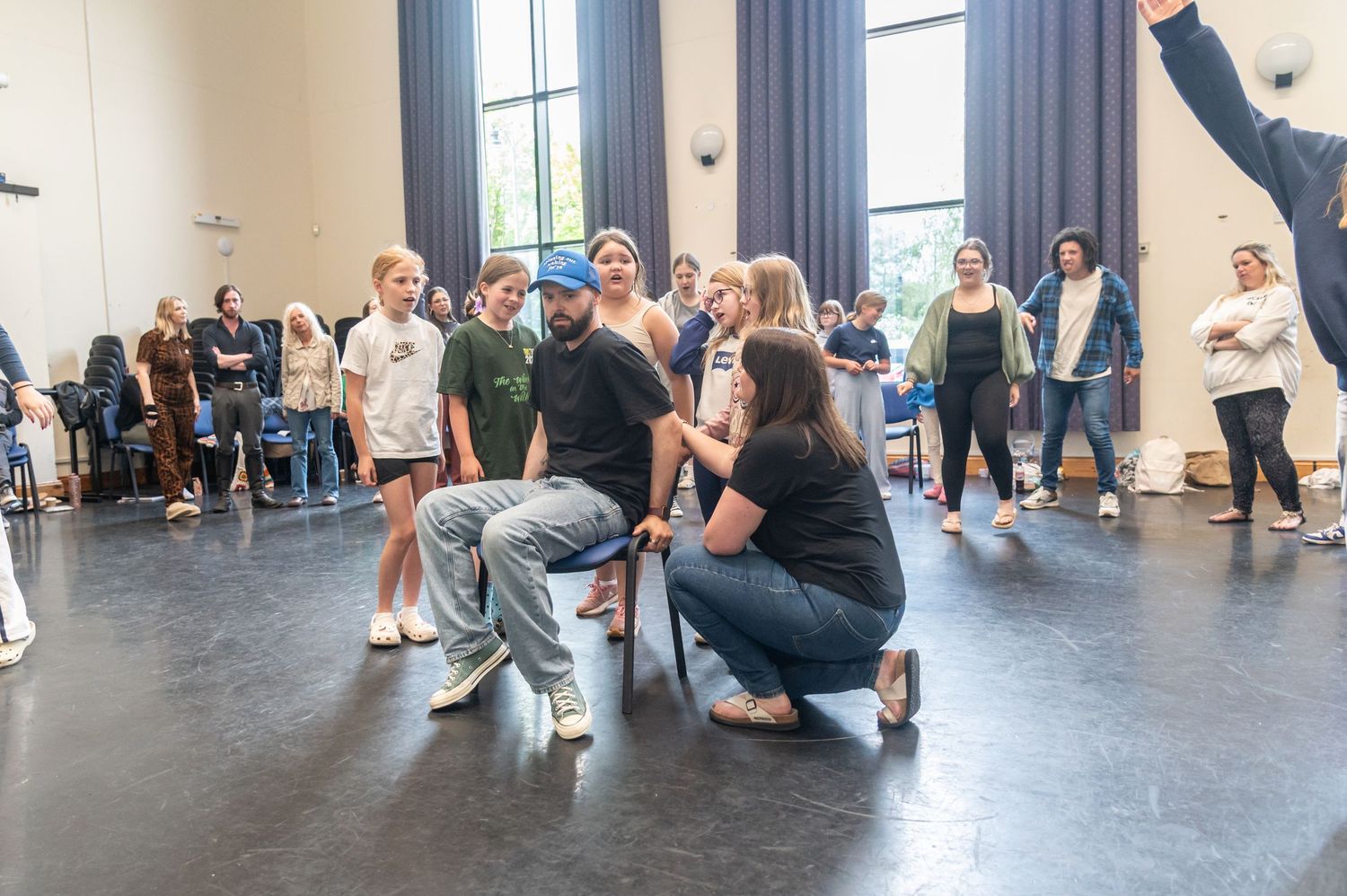 Group of dancers rehearsing in a spacious dance studio with natural lighting.