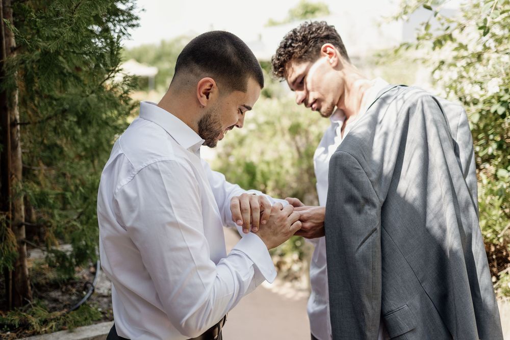 Two people share a tender moment looking down during a special outdoor occasion.