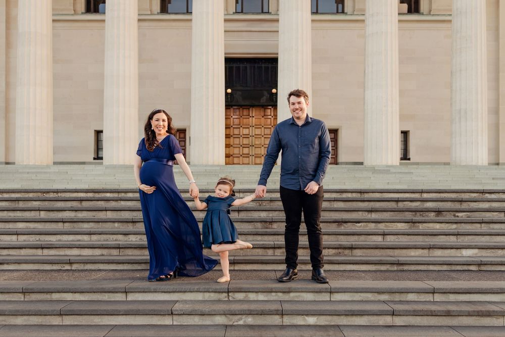 Well dressed Family holding hands standing on the steps outside the Auckland Museum for a family photoshoot. Catherine Lundin Photography