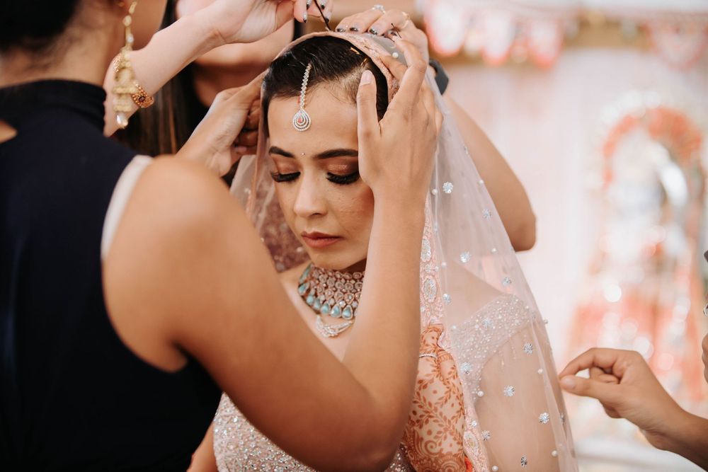 Wedding preparation scene with hands adjusting jewelry and veil details on bridal accessories.