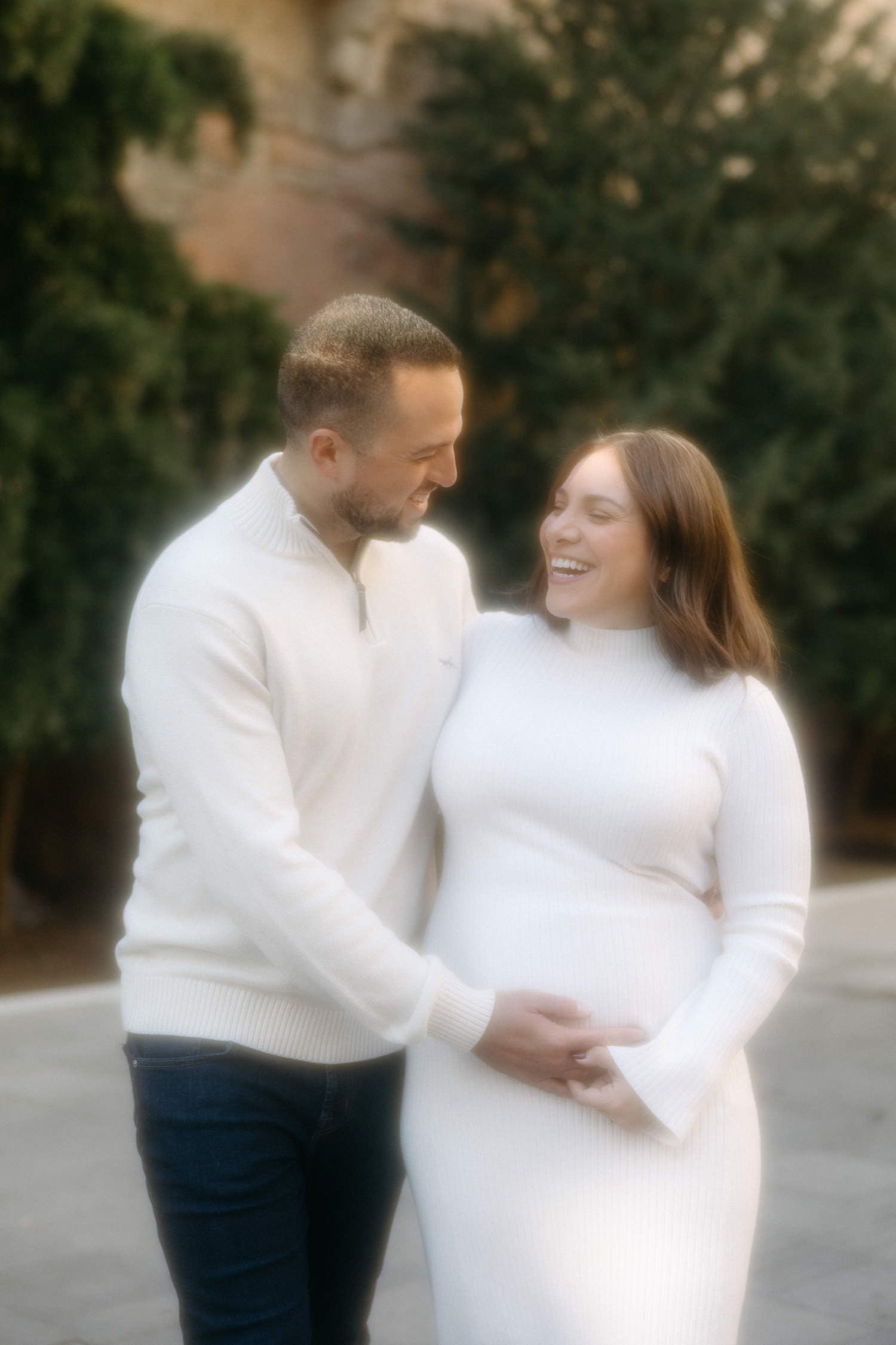 Dreamy maternity portraits with soft focus effect in outdoor setting.