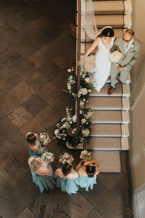 Bridal party gather on elegant stone staircase decorated with white floral arrangements at Saltmarshe Hall - taken by Grimsby photographers.