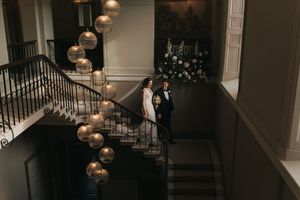 Bride and father descend down elegant staircase with cascading gold balloon decorations at Saltmarshe Hall - taken by Grimsby photographer.