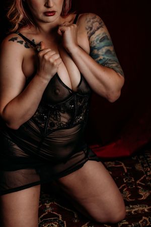 Artistic boudoir photos showing dark lingerie and tattoos in moody lighting against dramatic shadows. boudoir photographer grand rapids