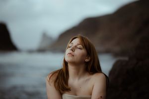 A dreamy portrait of a bride by the ocean coast with moody overcast skies. Playa de Benijo. Love Story in Tenerife.