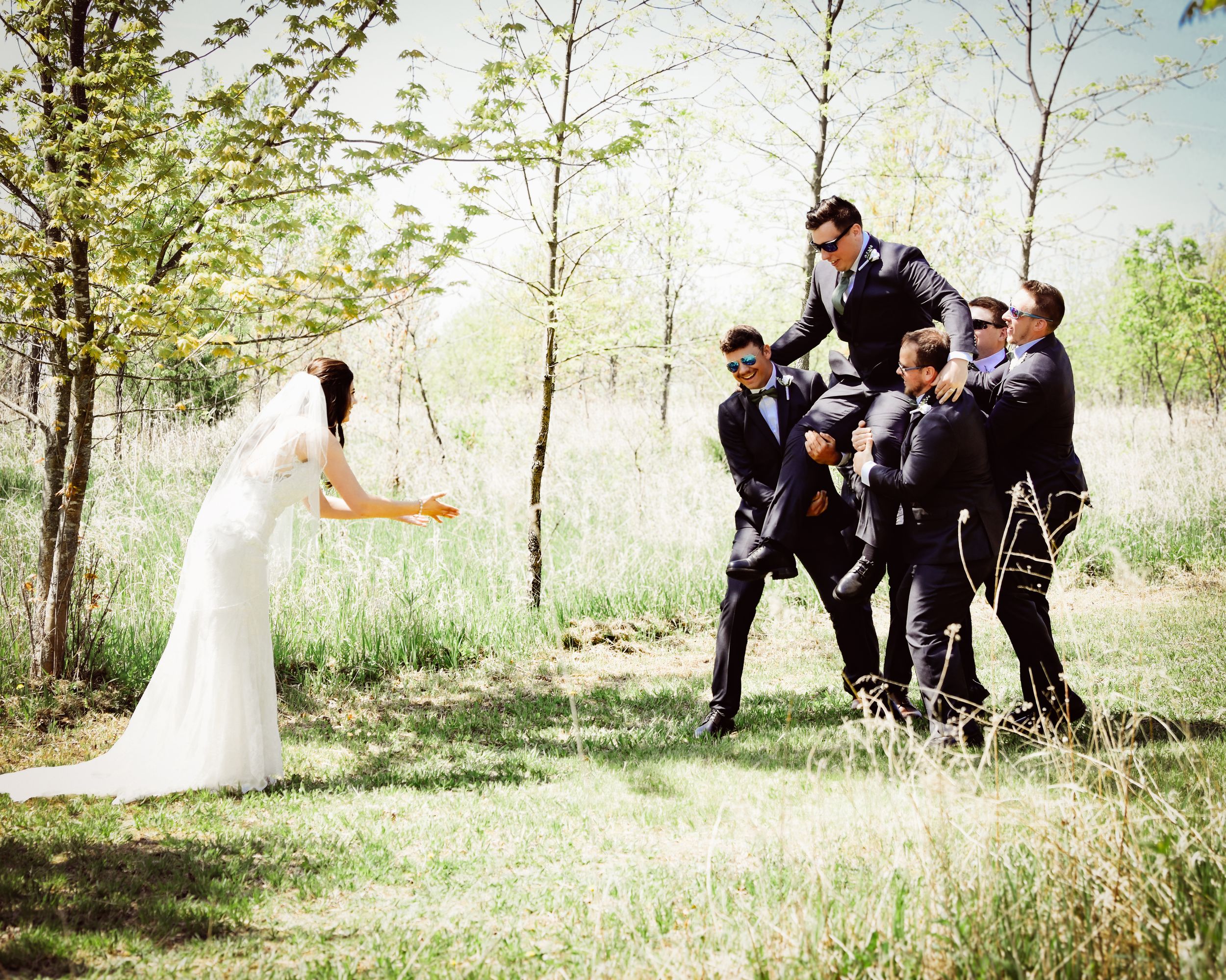 Wedding party having fun and posing playfully in a spring meadow setting.