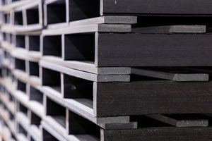 Stacked rows of dark industrial steel I-beams shown in a close-up perspective.