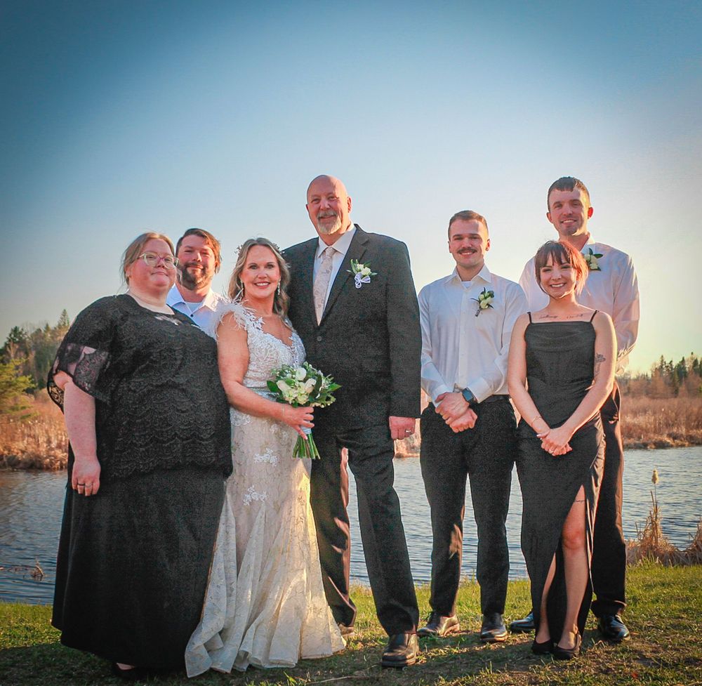 Wedding party poses together outside at sunset by a waterfront location.