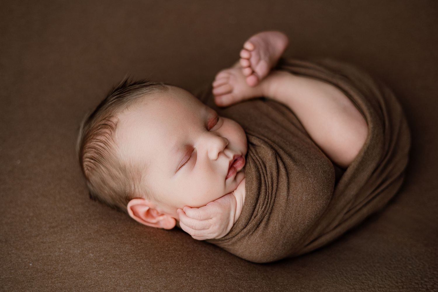 A collection of artistic baby photos in blue wrapping against a gingham checkered background shows a playful sequence.