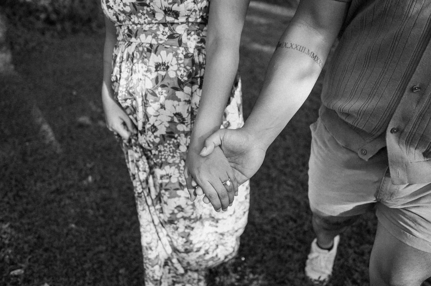 A black and white close-up of two people holding hands.