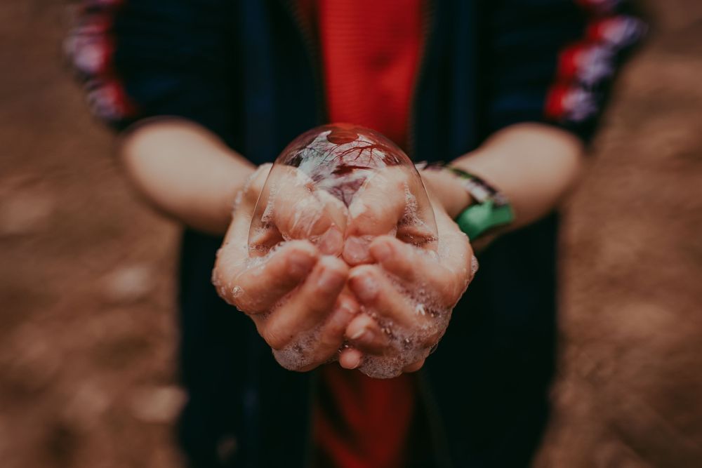 Cupped hands hold a giant bubble against a dark background. Arizona photographer, Whitney Popp