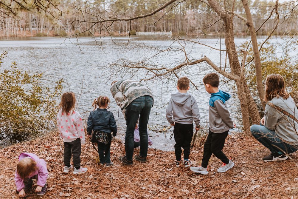 A group of people stand at the edge of a lake on an autumn day looking at the water through fallen leaves. Whitney Popp, Arizona