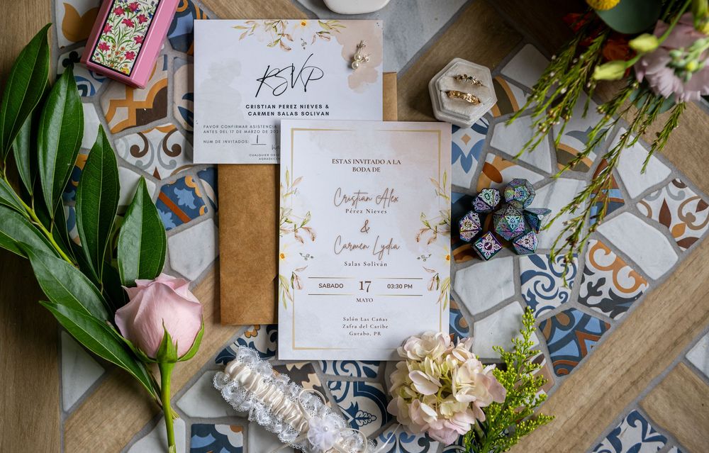 Wedding stationery and floral arrangements laid out on a rustic wooden surface with decorative elements.