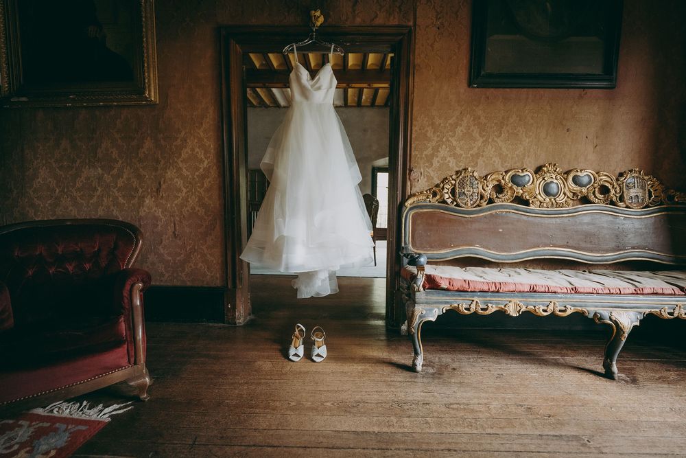 Vestido de novia colgado en habitación rústica en el Palacio de Valdesoto