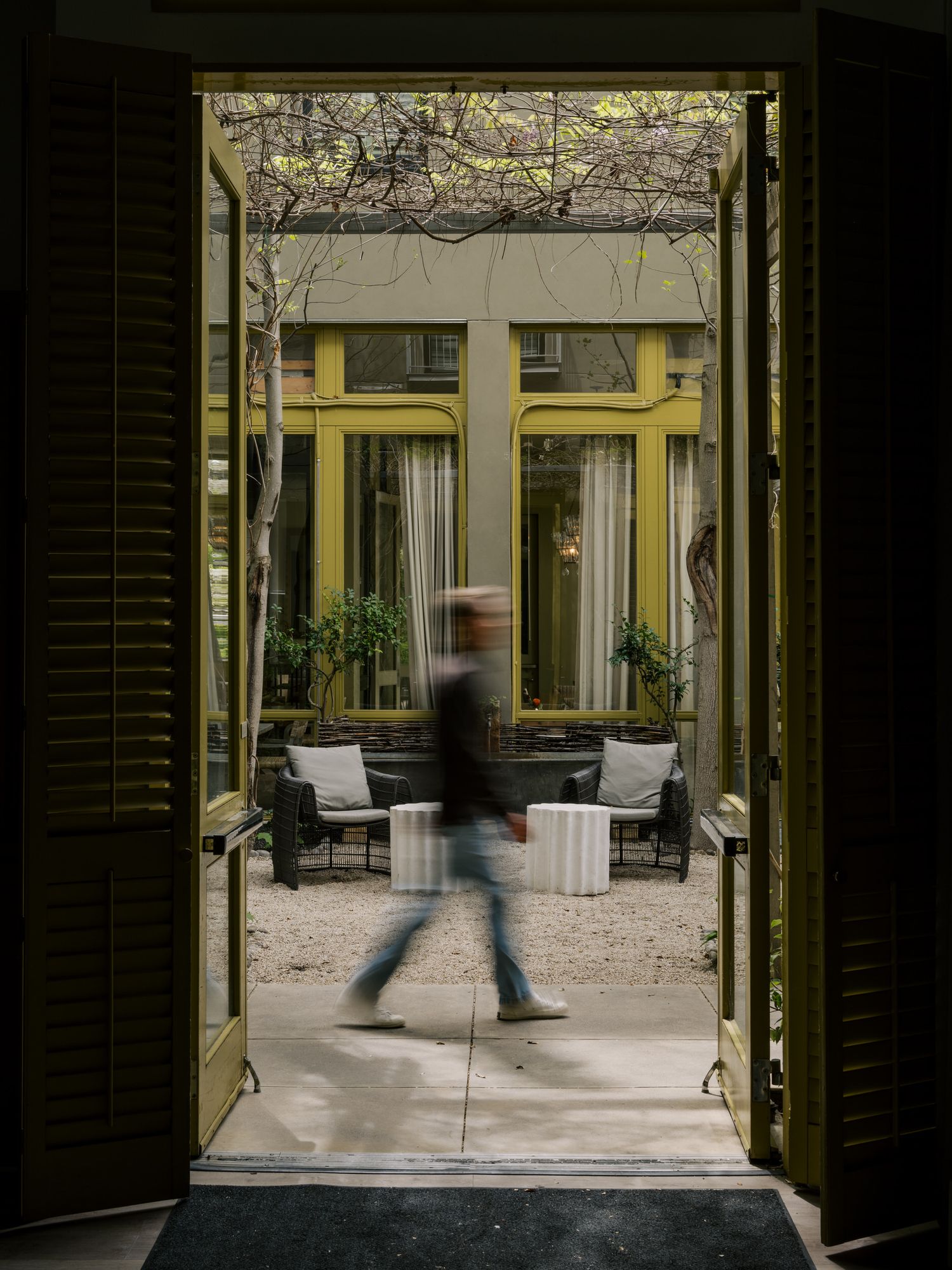 Motion blur of person walking through a modern building corridor with yellow walls and glass doors.