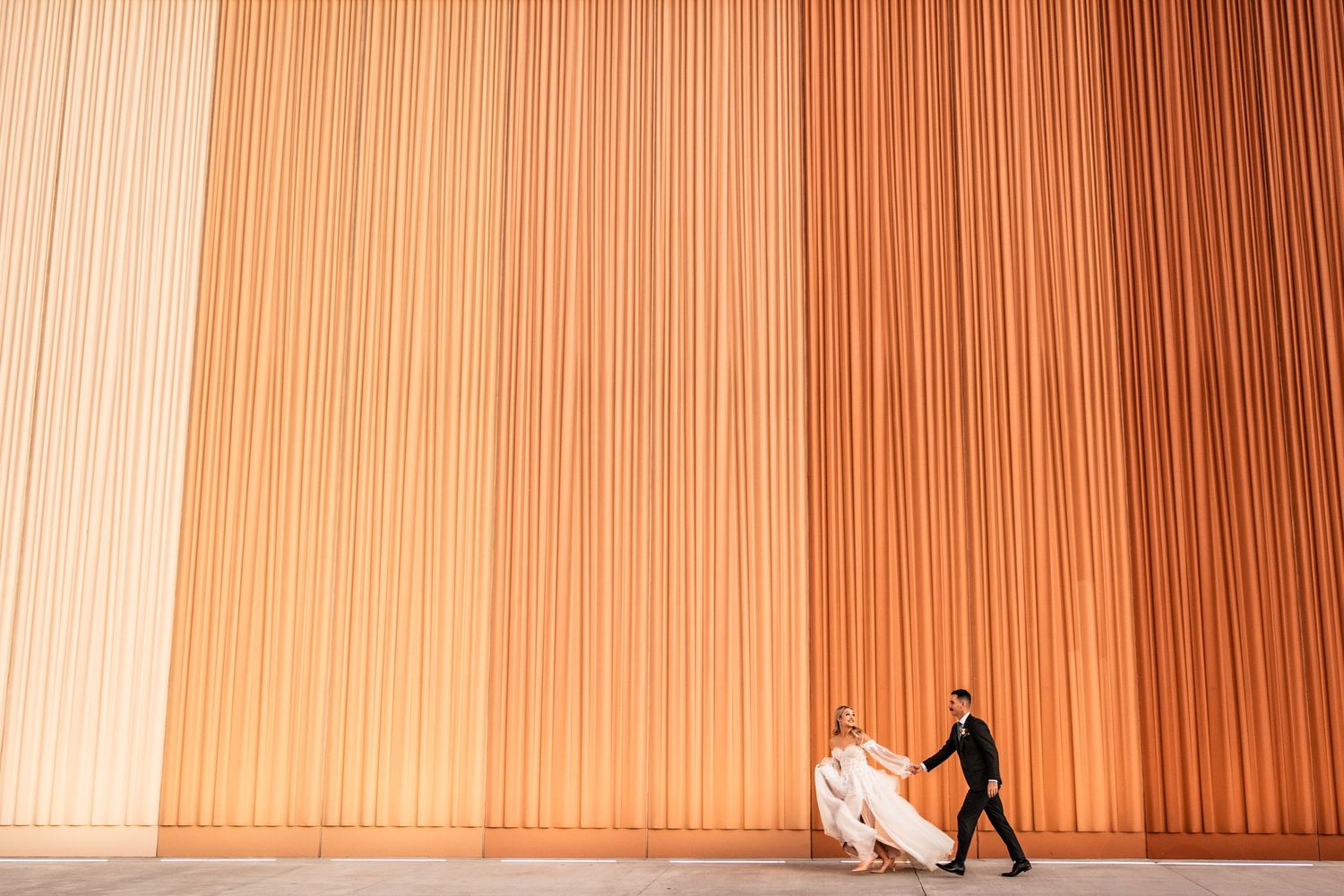 Bride and groom running with a huge backdrop at Agri food Hub and Trade Centre