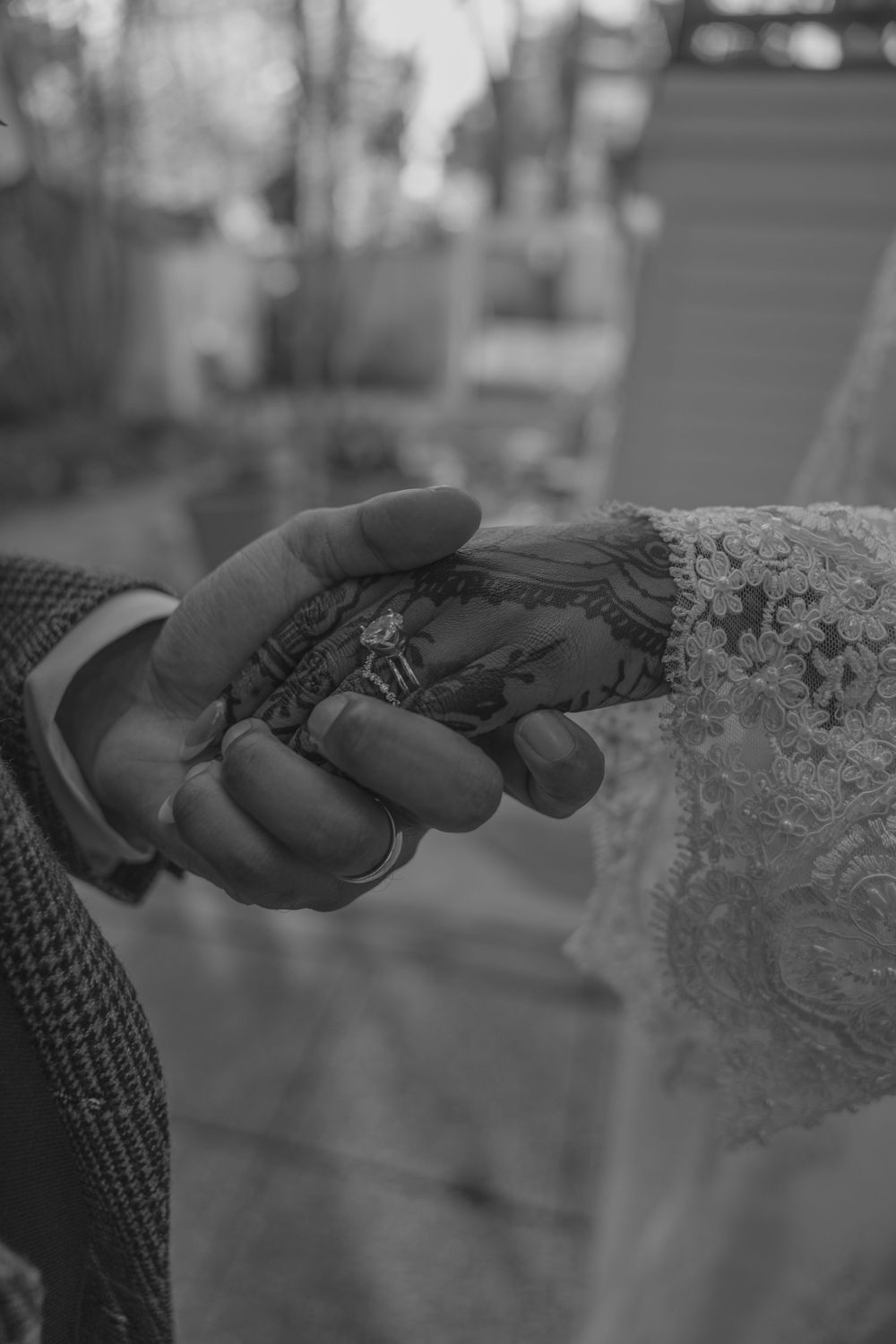 Close-up black and white photo of hands holding delicate lace fabric at a wedding.