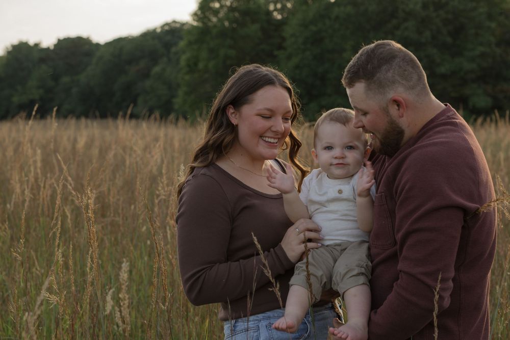 A family sharing a joyful moment together in a golden wheat field at sunset.
