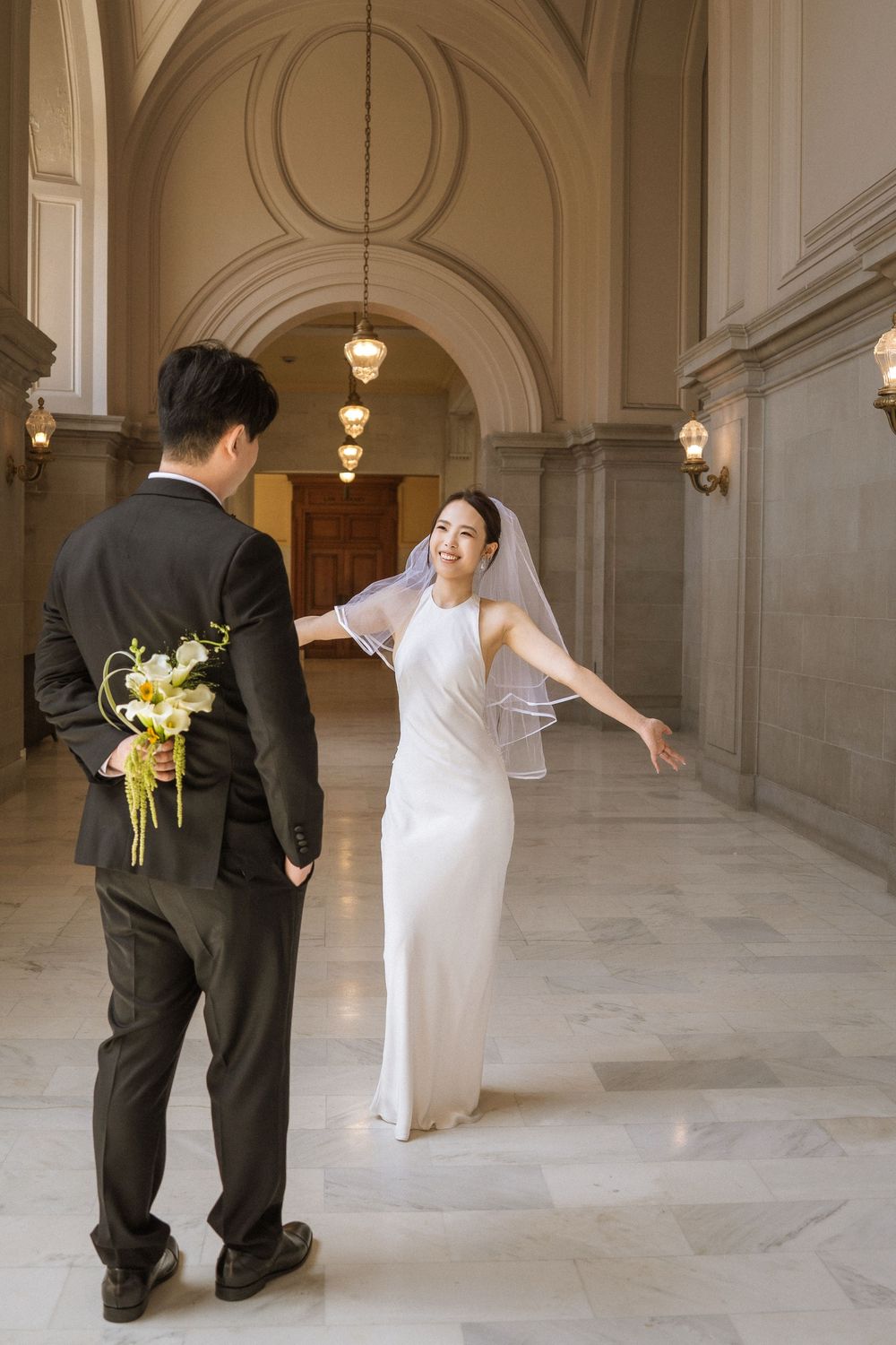 A sequence of four wedding photos showing playful interactions between a bride in white and groom in black in an elegant hallway.