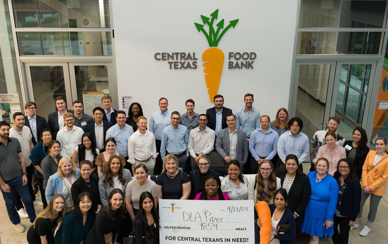 Group corporate photo in front of Central Texas Food Bank signage