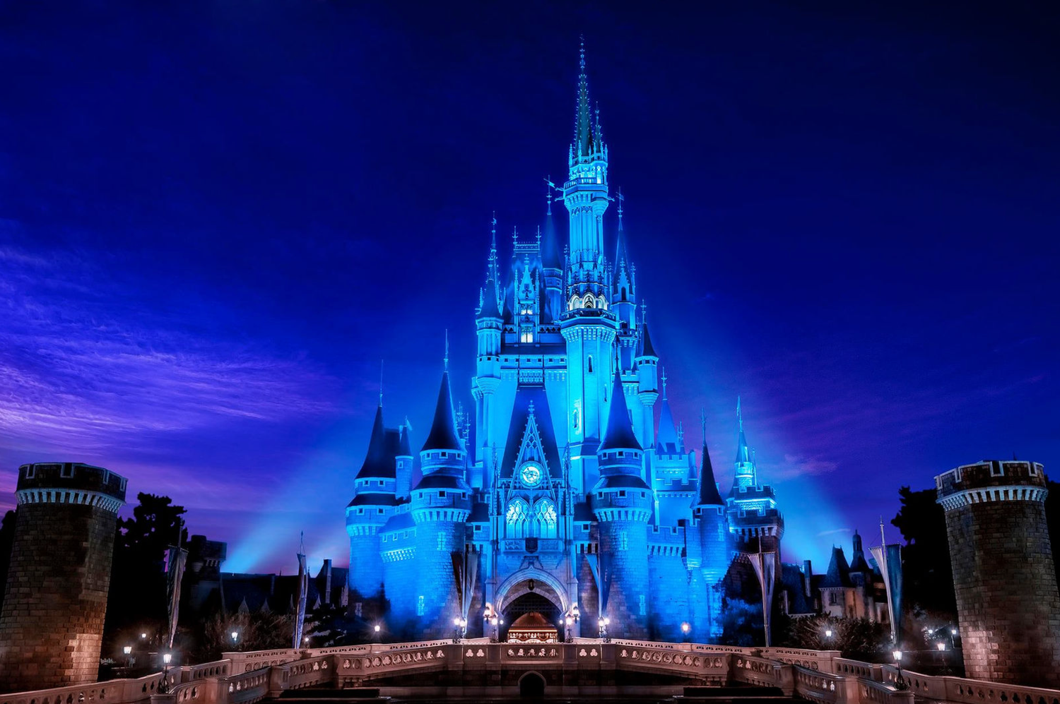 Cinderella Castle illuminated in blue lights against a night sky at Disney World.