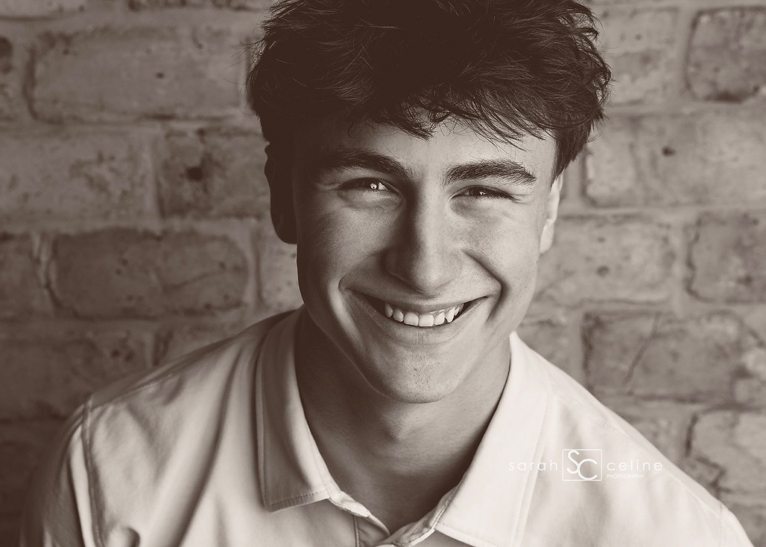 A series of black and white headshot photographs arranged horizontally against a textured brick wall background.