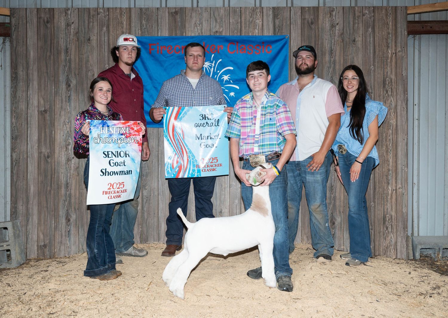 Group of people standing against wooden wall at county fair event.