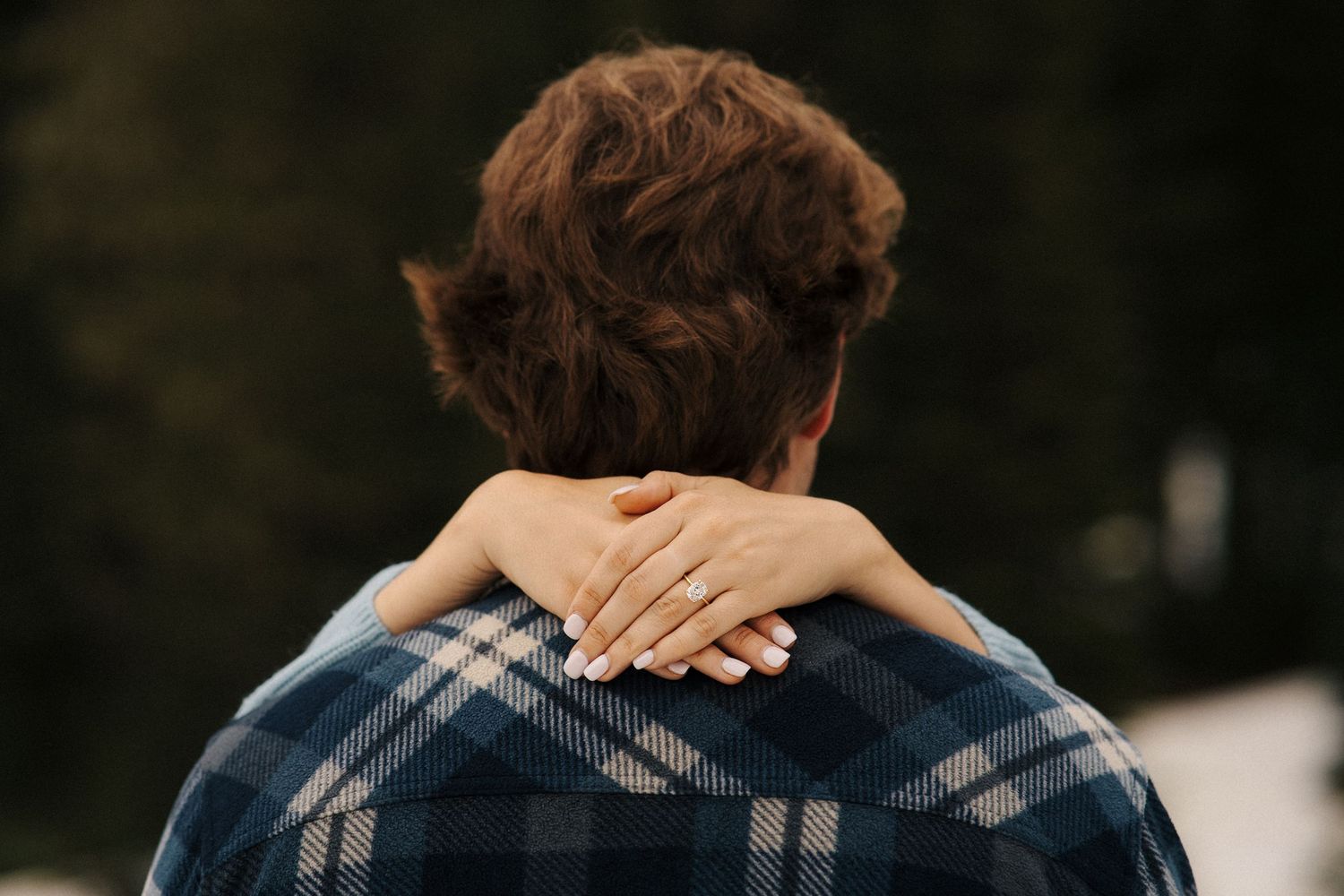 Back view of someone wearing a plaid flannel shirt with hands crossed behind their head.