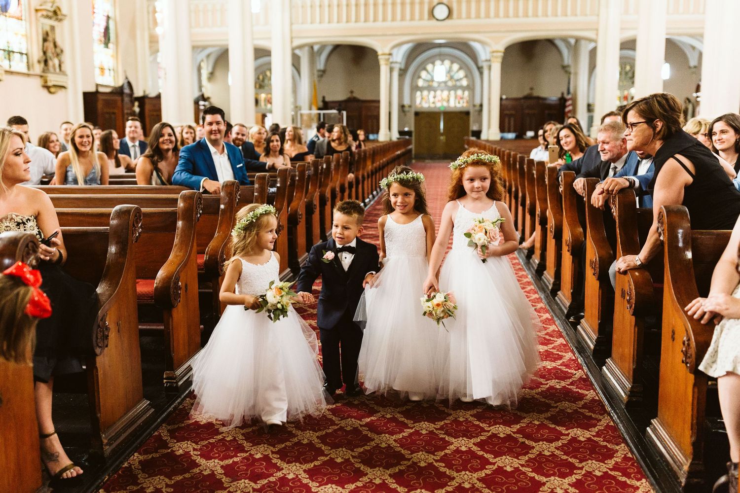 Wedding ceremony in progress inside a historic church with ornate wooden pews and traditional decor.