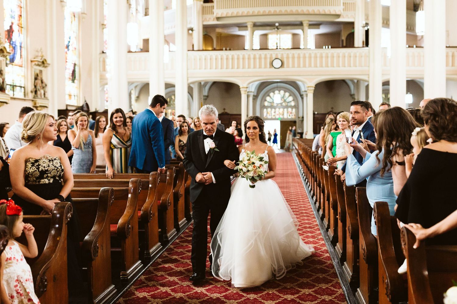 Panoramic view of a traditional church wedding ceremony with guests seated in wooden pews.