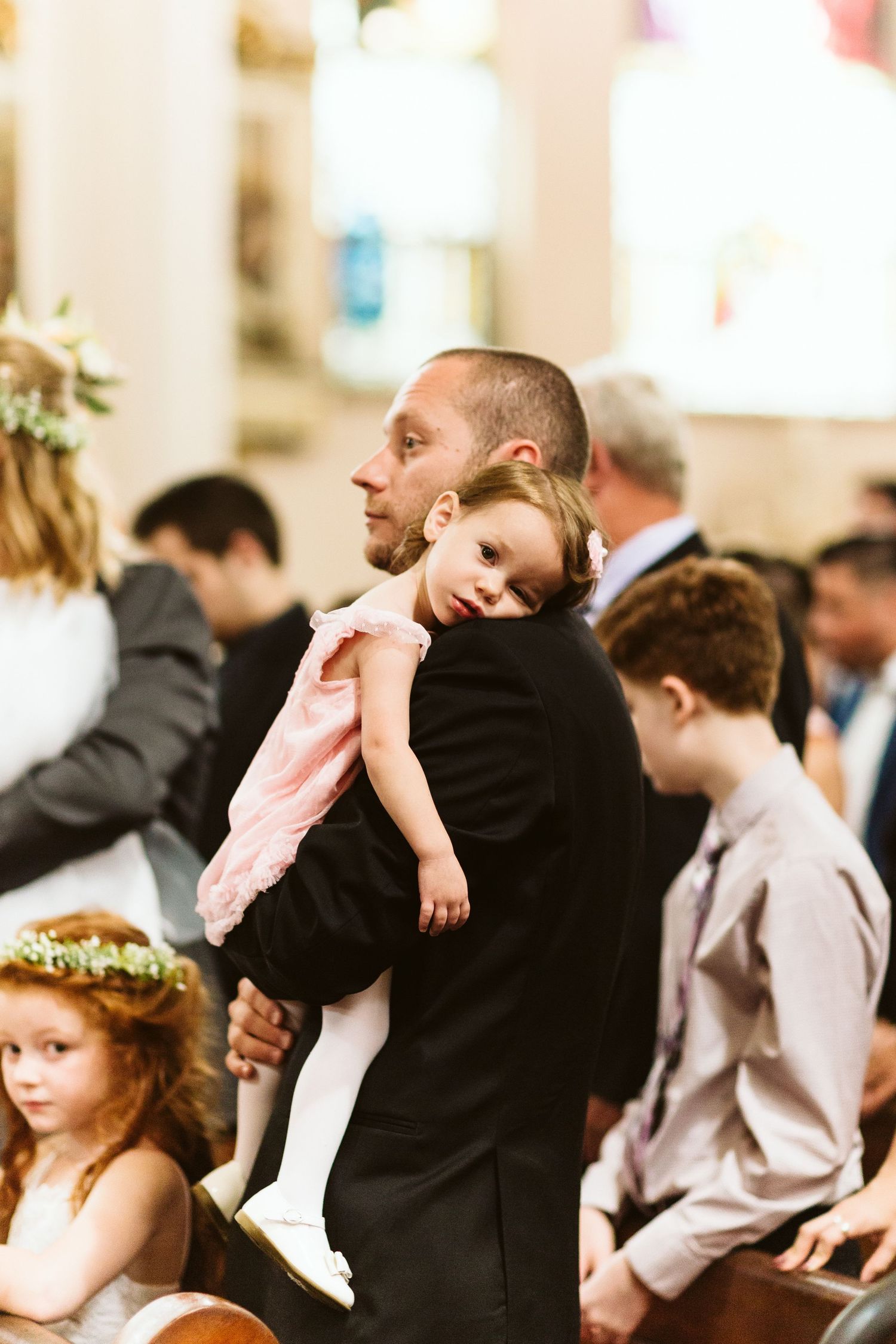 Wedding guests and children seated in church pews during a traditional ceremony.