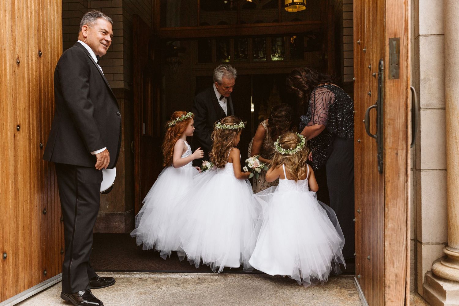 Wedding ceremony procession enters through grand wooden doors of a traditional church.