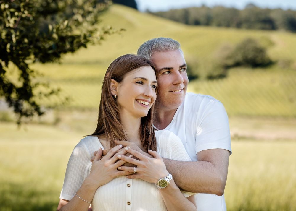 A couple shares tender moments in a sunny meadow during their engagement photoshoot in the countryside.