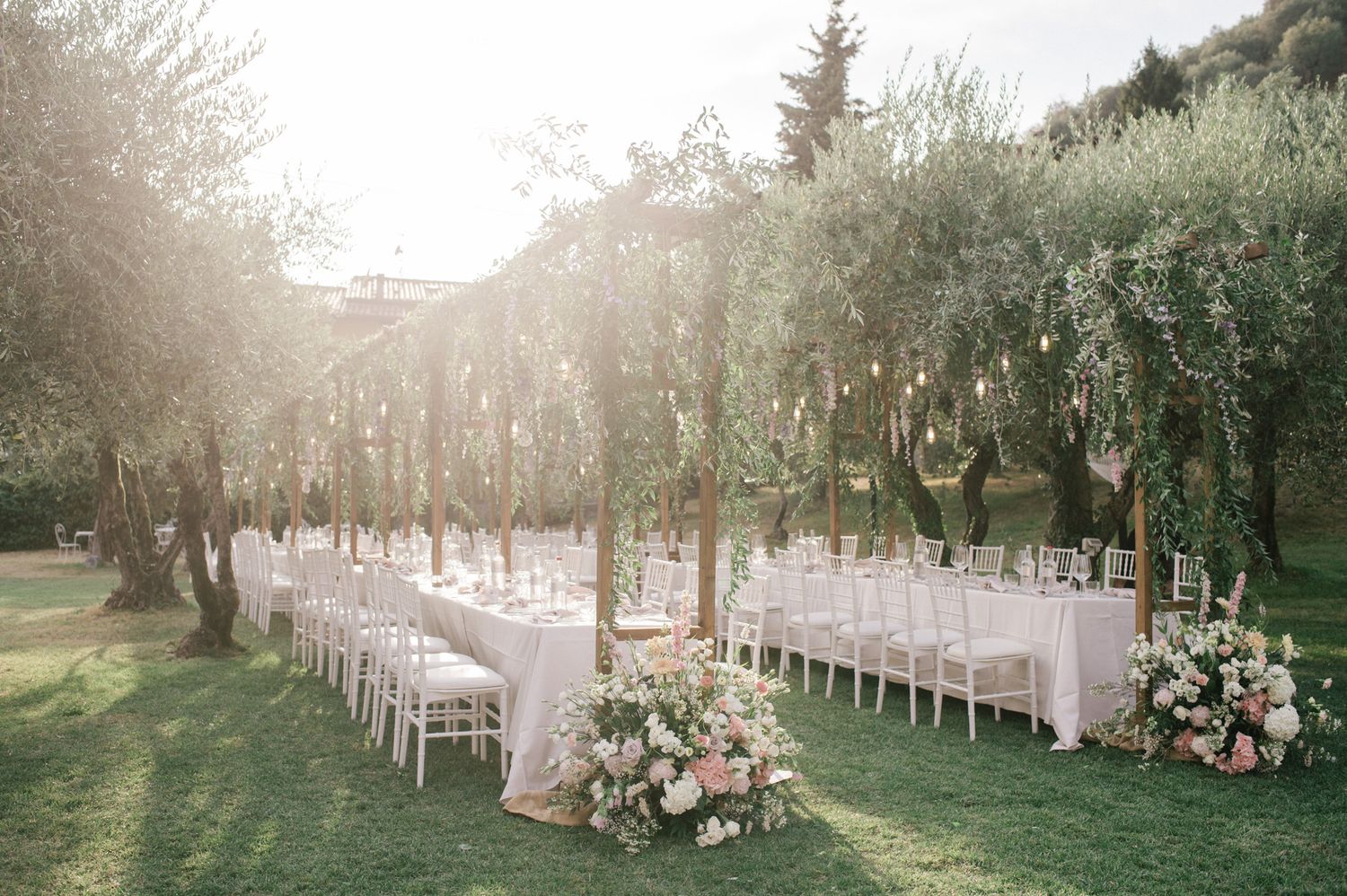 Olive garden wedding reception with wooden structures and floral decor on Lake Iseo