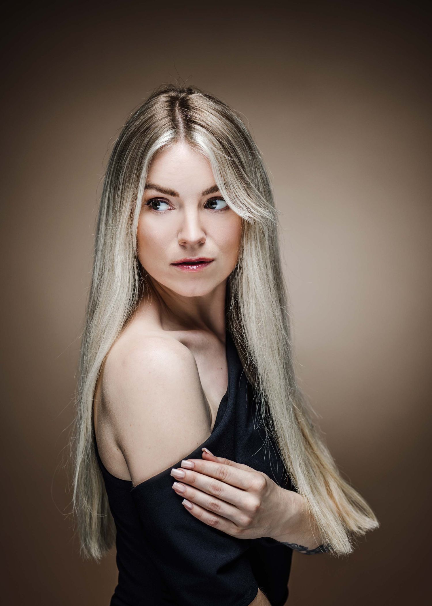 A series of artistic portrait photos showing a person with platinum blonde hair wearing a black top against a dark background.