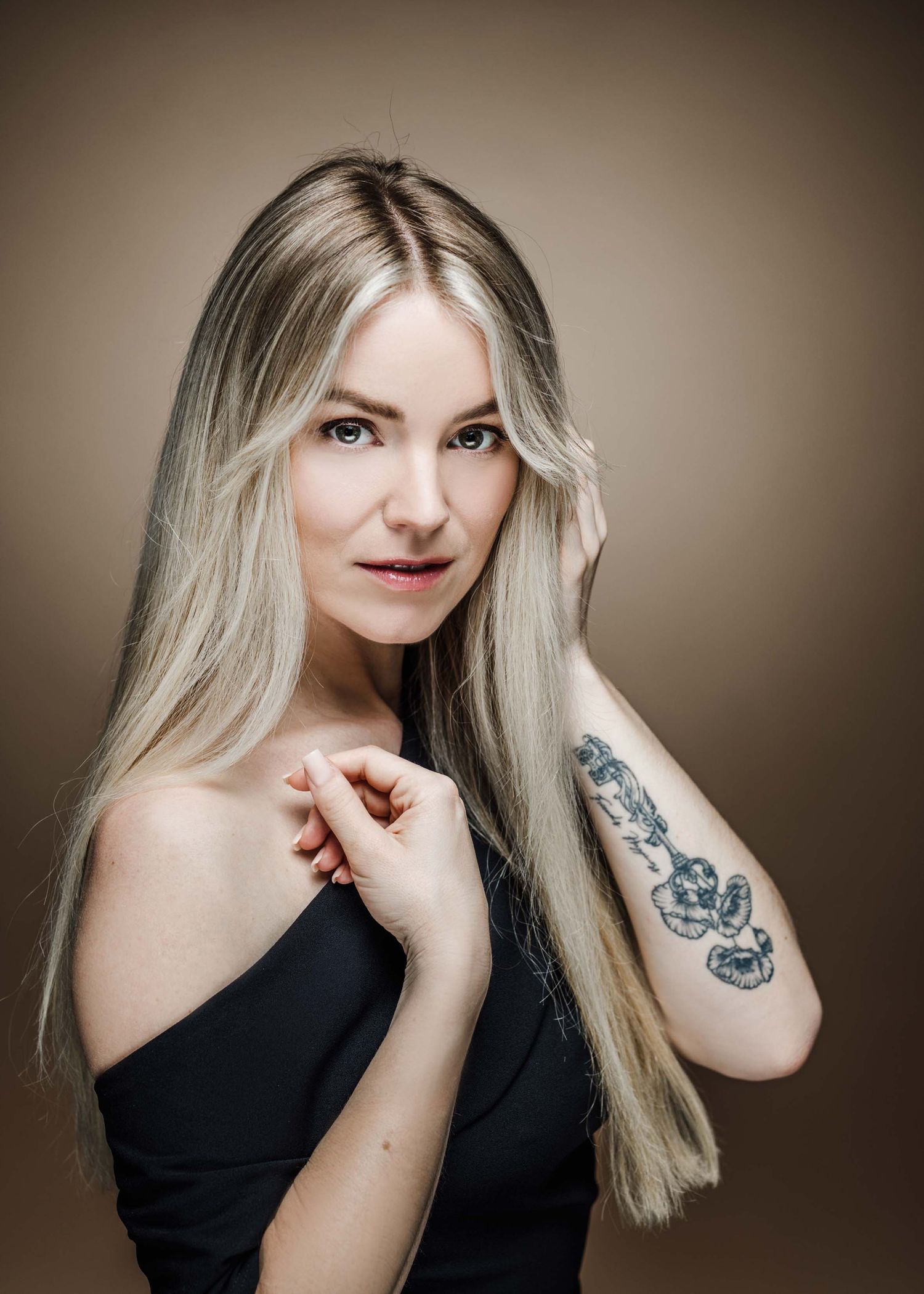 A series of four artistic portraits showing a woman in black attire with blonde hair and visible tattoos against a neutral background.