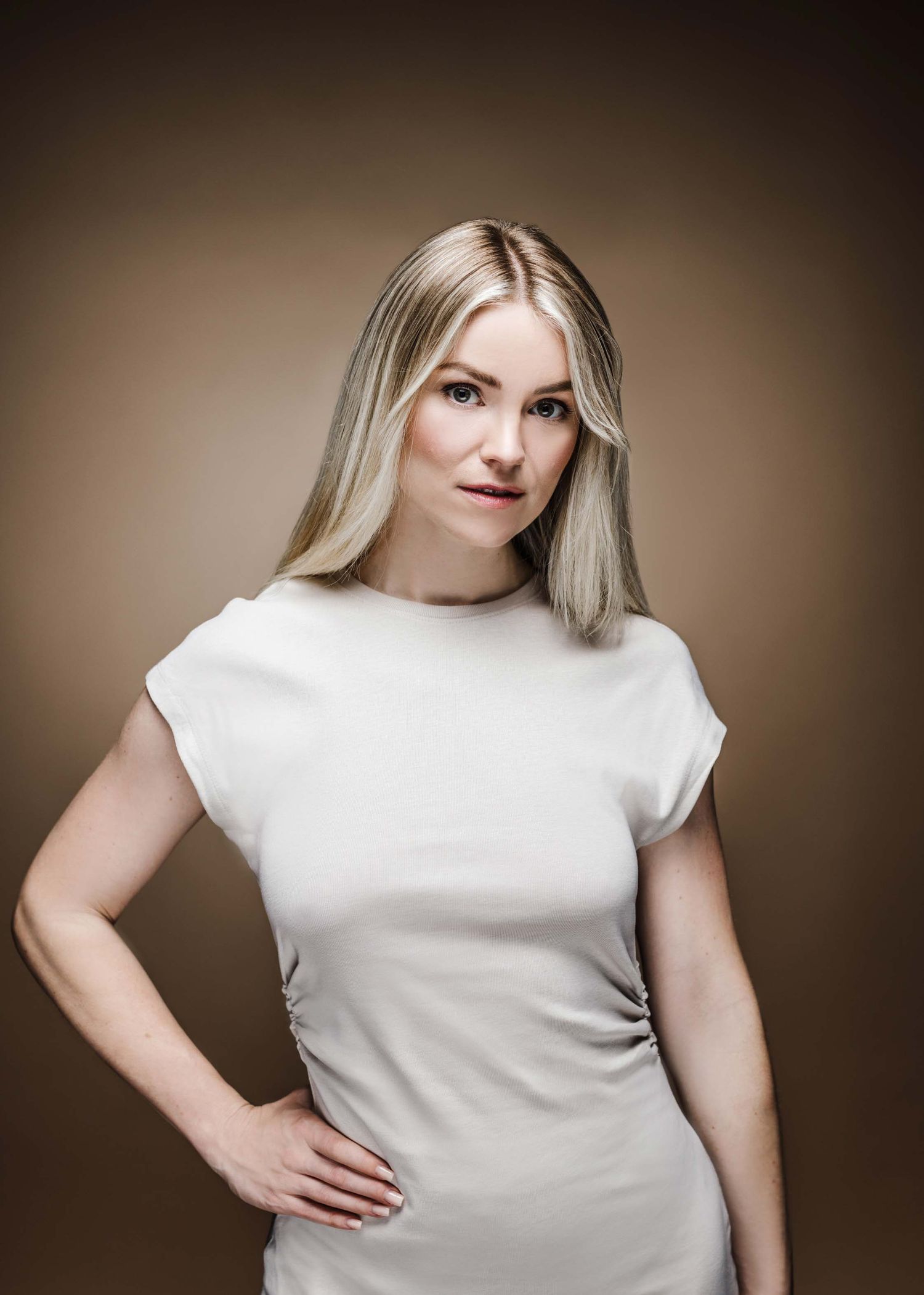 A woman in a white t-shirt poses against a brown backdrop in a series of similar fashion shots.