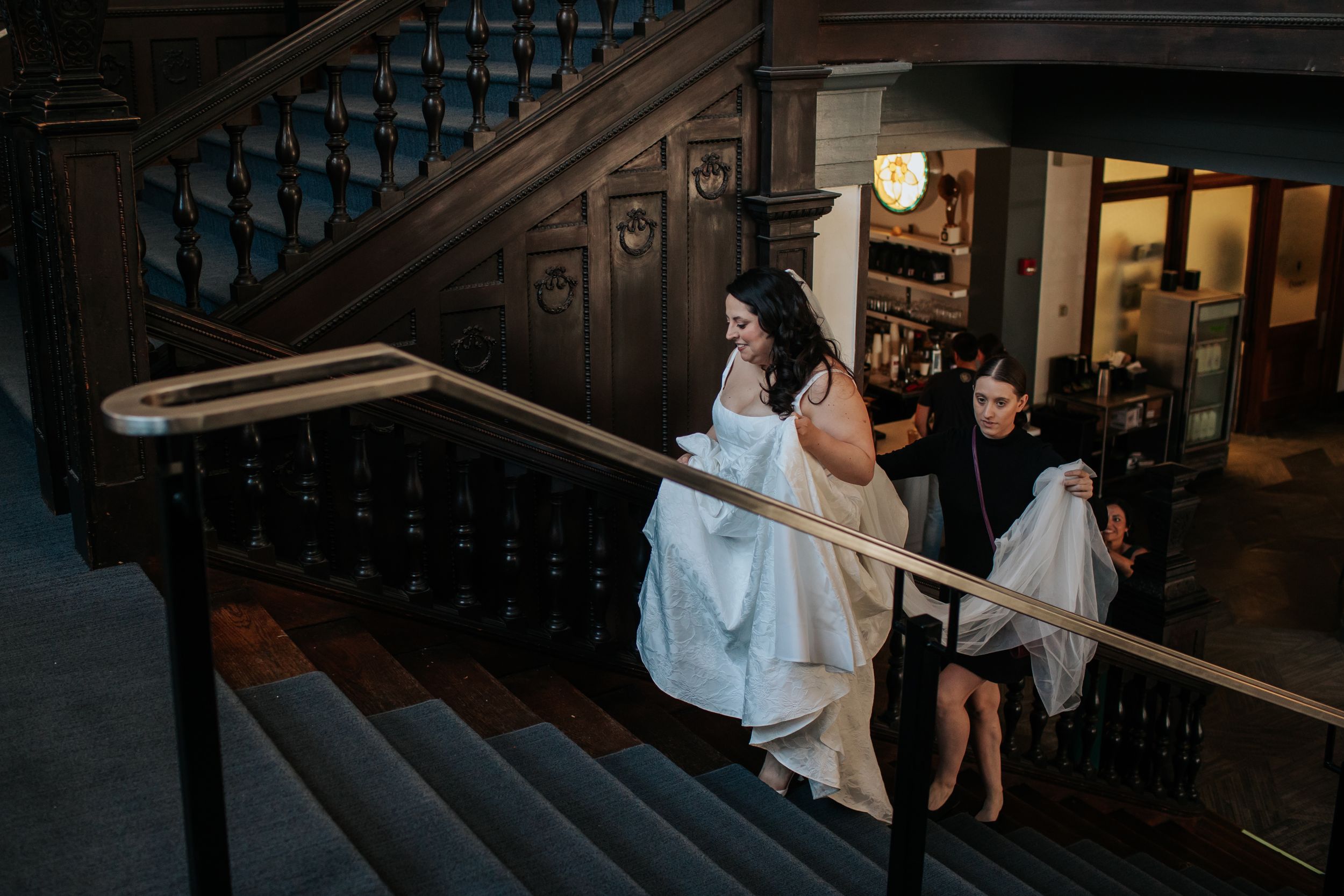 Wedding party poses on elegant wooden staircase in formal attire during indoor celebration.