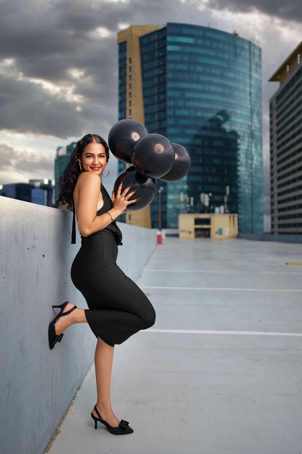 A sequence of dynamic poses with a black bowling ball against a backdrop of modern office buildings on a rooftop.
