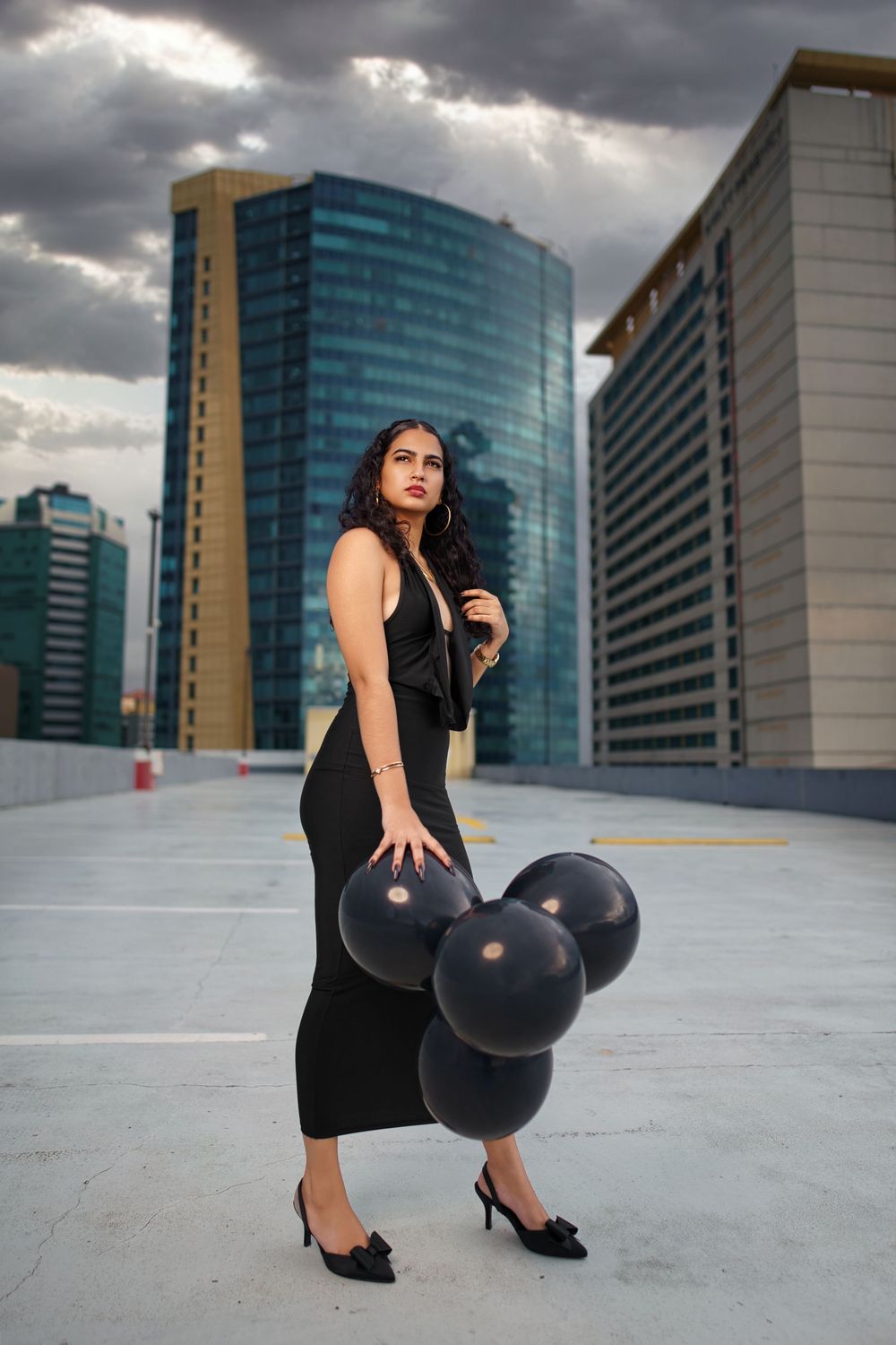 A series of athletic movements with a bowling ball on an urban rooftop with glass buildings in the background.