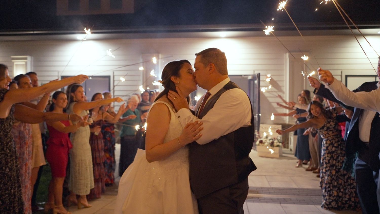 Wedding reception dance with guests holding sparklers creating a glowing tunnel effect.